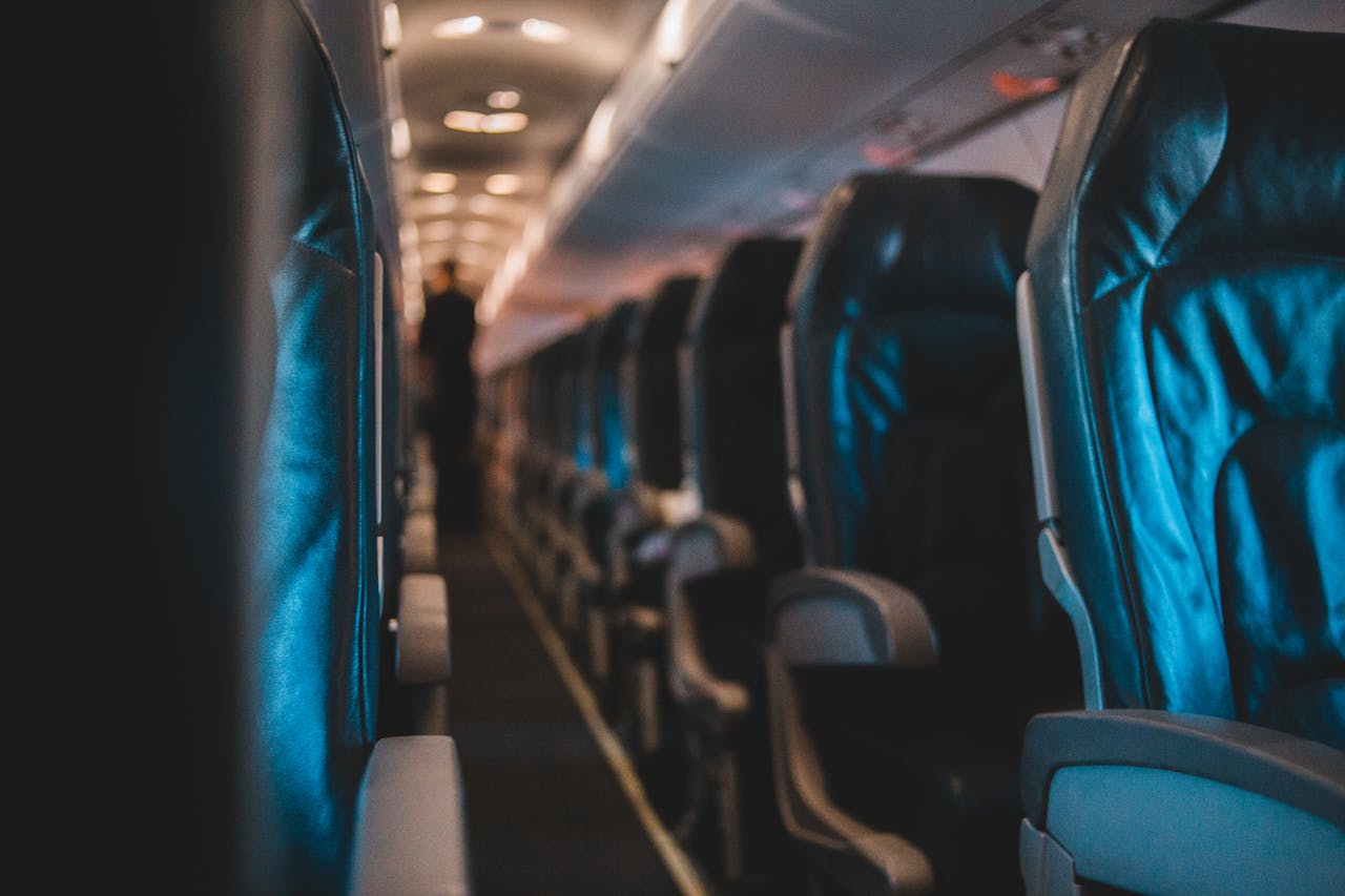 Interior view of an empty airplane cabin with leather seats and soft lighting.